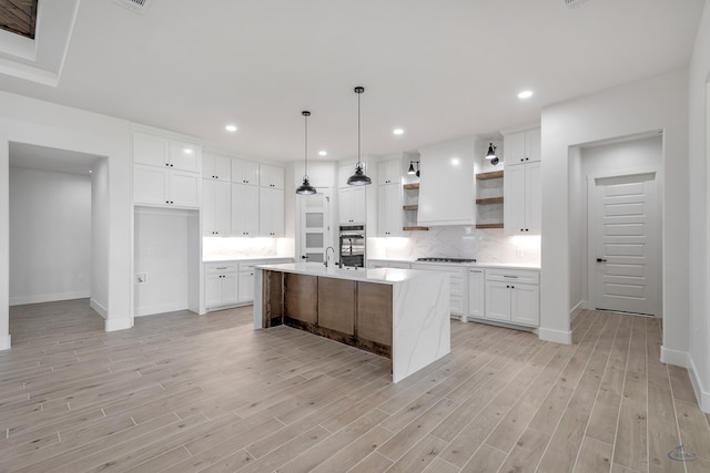 kitchen with a center island with sink, white cabinetry, gas stovetop, and light hardwood / wood-style floors