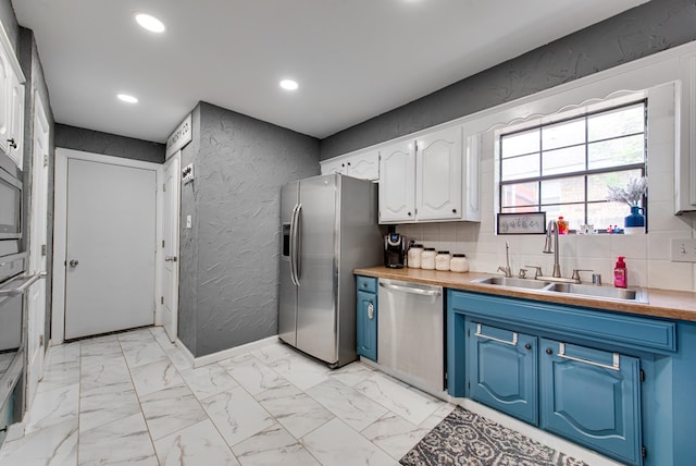 3906 Lehigh Dr, Midland, TX 79707 - kitchen featuring appliances with stainless steel finishes, a sink, blue cabinets, a textured wall, and recessed lighting