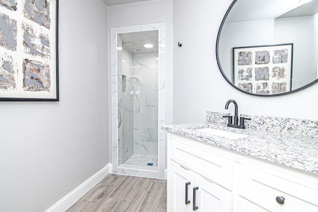 bathroom featuring a shower stall, vanity, baseboards, and wood finished floors