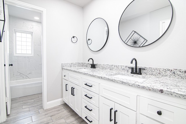 bathroom with hardwood / wood-style flooring, vanity, and tiled shower / bath