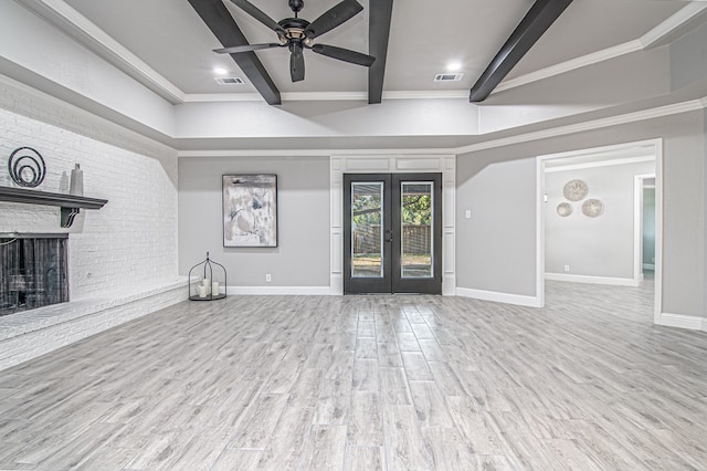 unfurnished living room with french doors, a brick fireplace, ceiling fan, beamed ceiling, and light hardwood / wood-style floors