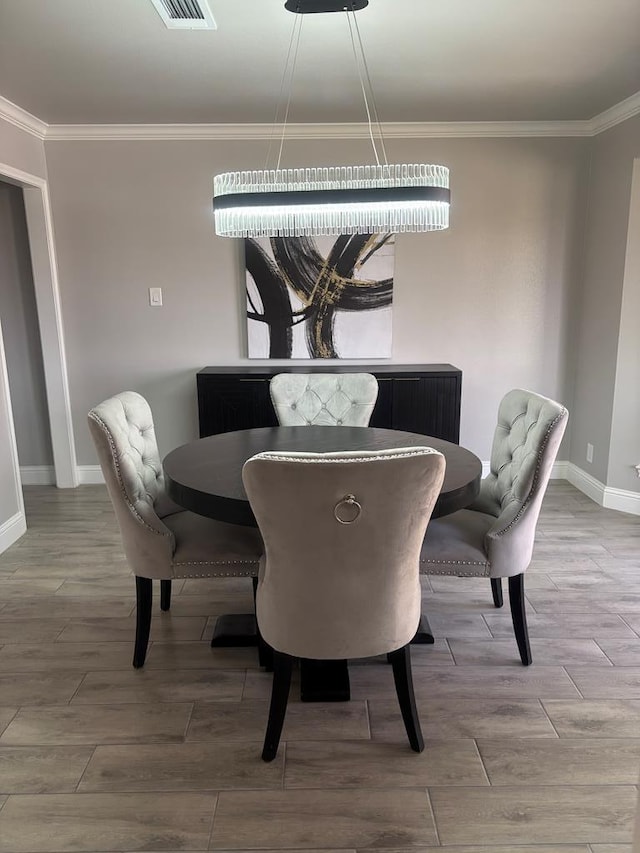 dining room featuring visible vents, crown molding, baseboards, and wood finished floors