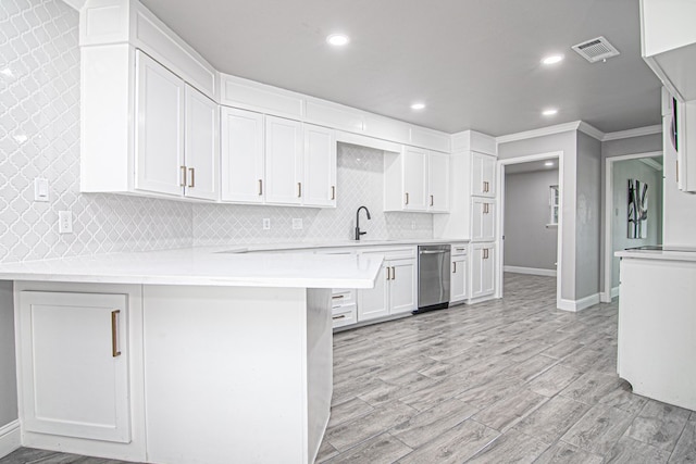 kitchen with tasteful backsplash, visible vents, light countertops, a peninsula, and white cabinets