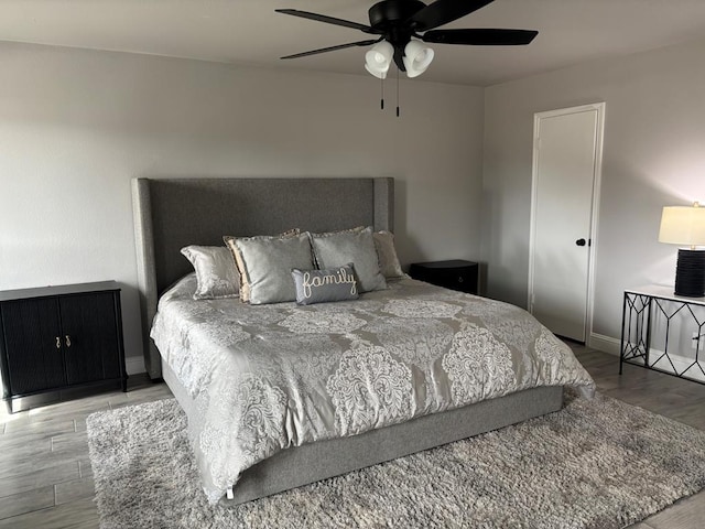 bedroom with a ceiling fan, wood finished floors, and baseboards