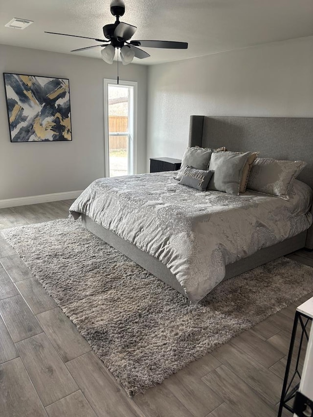 bedroom with visible vents, ceiling fan, baseboards, wood finished floors, and a textured ceiling