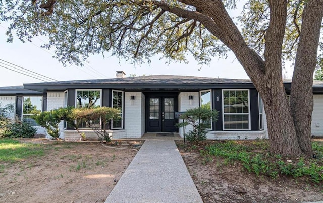 single story home featuring french doors, brick siding, and a chimney