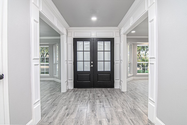 entryway with crown molding, light wood-style flooring, french doors, and baseboards