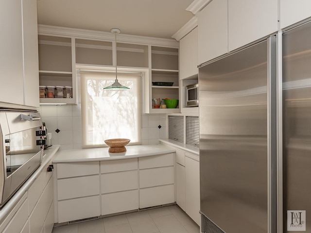 kitchen with backsplash, pendant lighting, light tile patterned floors, white cabinets, and built in refrigerator