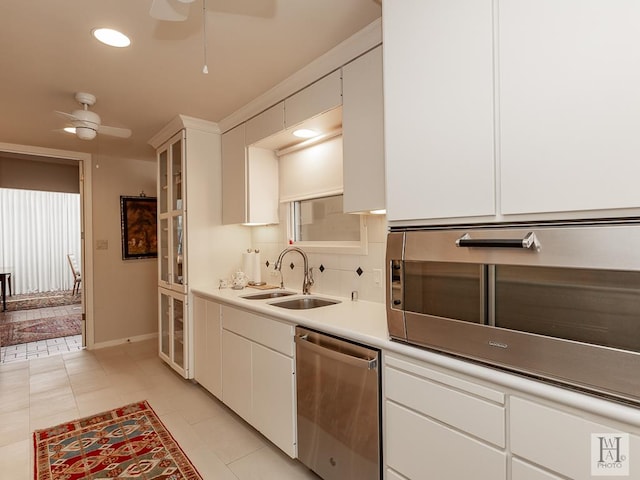 kitchen featuring backsplash, stainless steel dishwasher, sink, light tile patterned floors, and white cabinets