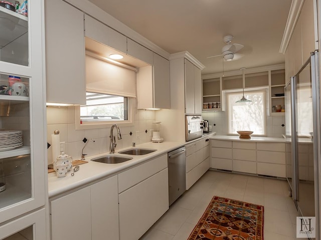 kitchen featuring stainless steel dishwasher, sink, white cabinetry, hanging light fixtures, and light tile patterned flooring