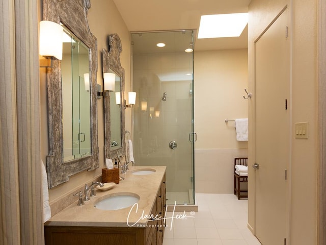 bathroom featuring vanity, a skylight, tile patterned floors, and an enclosed shower