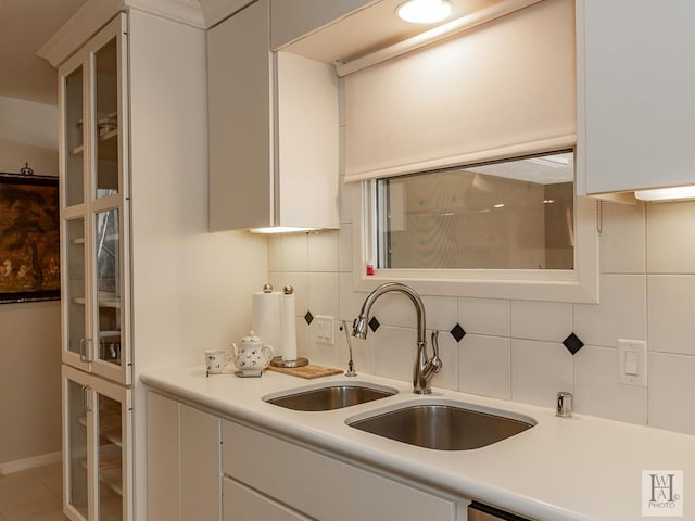 kitchen featuring tasteful backsplash, white cabinetry, and sink