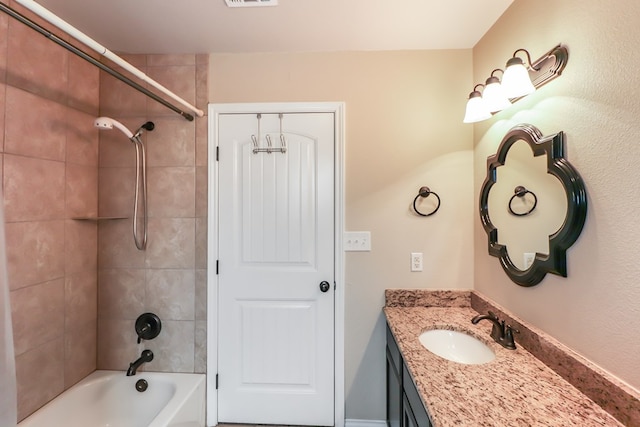 bathroom with tiled shower / bath and vanity