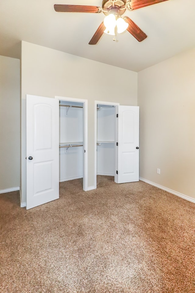 unfurnished bedroom featuring ceiling fan, carpet, and two closets