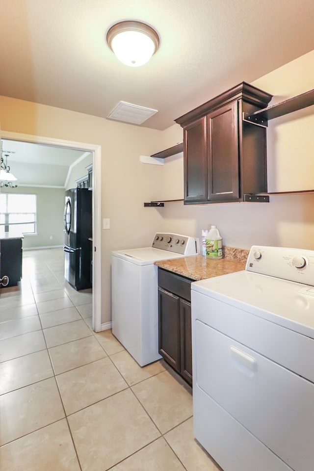 washroom featuring cabinets, washing machine and dryer, and light tile patterned floors