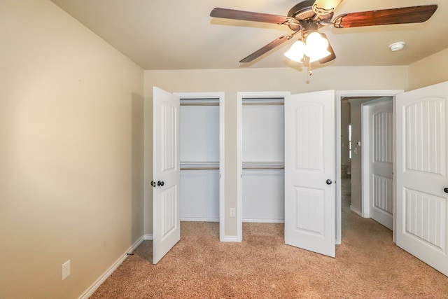 unfurnished bedroom featuring ceiling fan, light carpet, and two closets