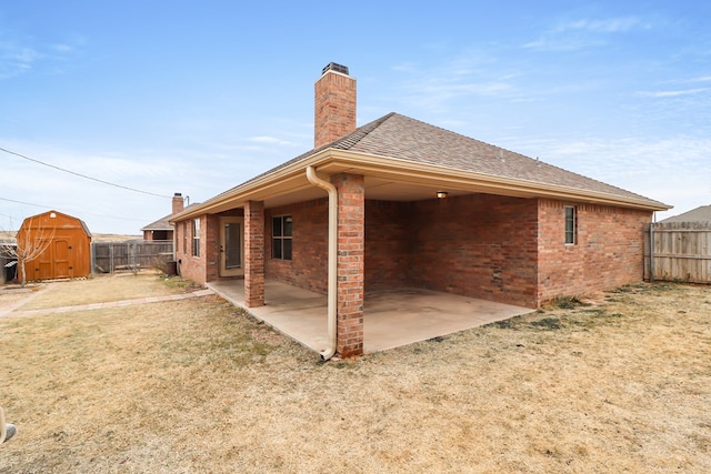 back of property with a patio, a yard, and a storage unit