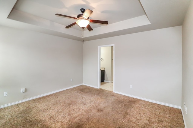 spare room with light carpet, a raised ceiling, and ceiling fan