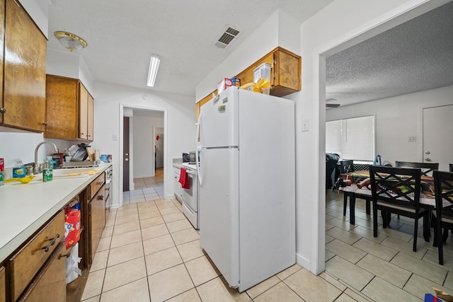 704 Birdwell Ln, Big Spring, TX 79720 - kitchen with white appliances, light tile patterned floors, brown cabinetry, light countertops, and a textured ceiling