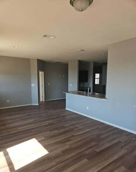 unfurnished living room featuring dark wood-style floors, visible vents, and baseboards