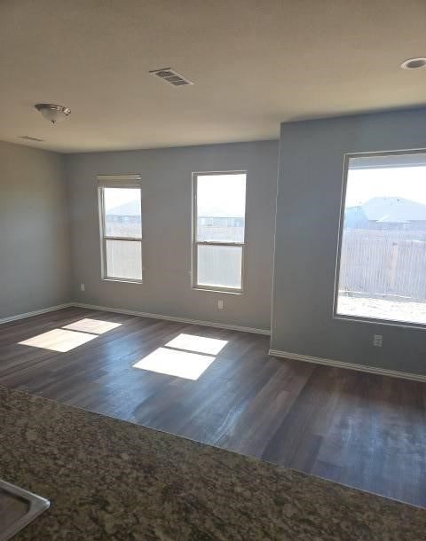 unfurnished room featuring baseboards, visible vents, and wood finished floors