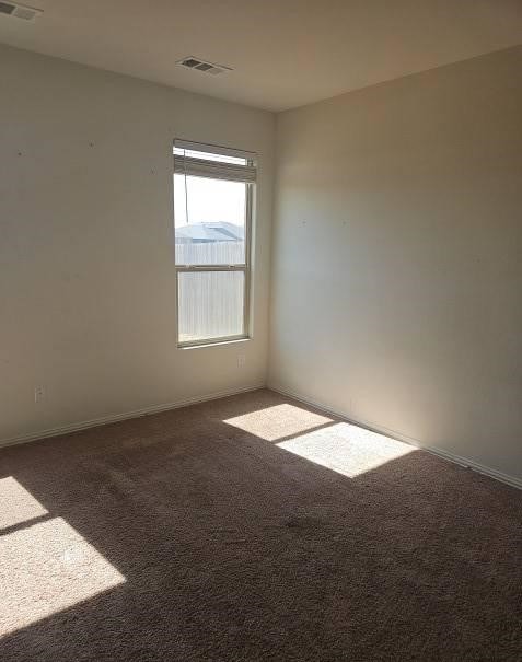 carpeted spare room featuring visible vents and baseboards