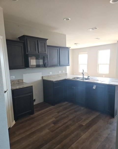 kitchen with a sink, visible vents, black microwave, and dark wood-style flooring