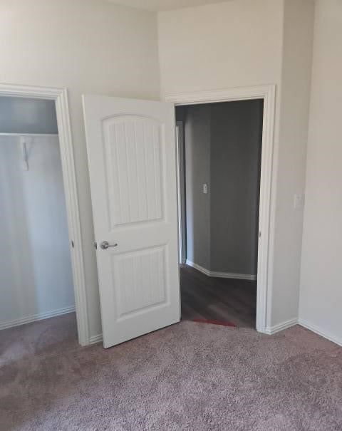 unfurnished bedroom with a closet, carpet flooring, and baseboards