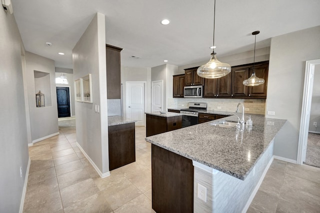 kitchen featuring appliances with stainless steel finishes, hanging light fixtures, sink, kitchen peninsula, and light stone counters