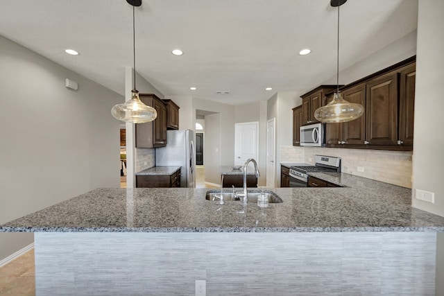 kitchen featuring sink, dark brown cabinetry, kitchen peninsula, pendant lighting, and stainless steel appliances