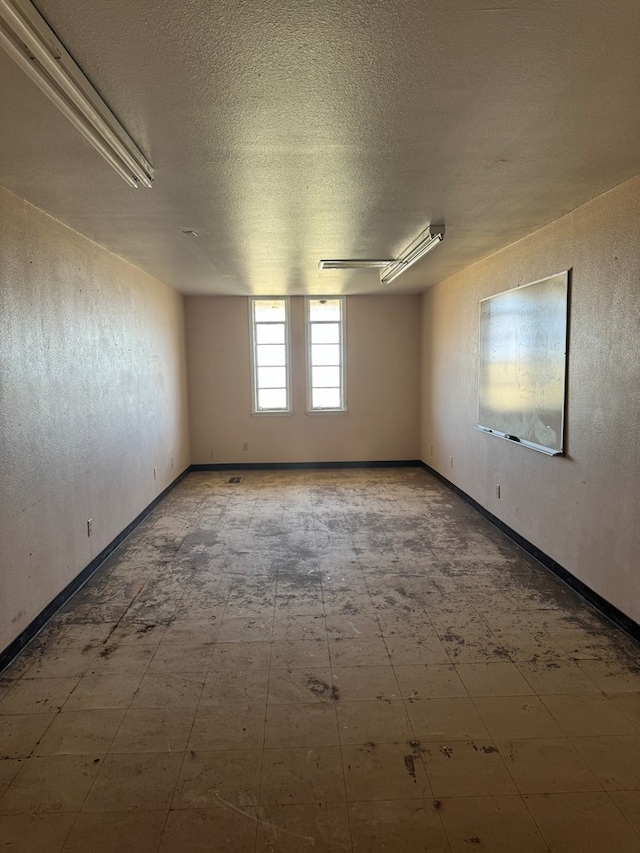 unfurnished room featuring a textured ceiling and baseboards
