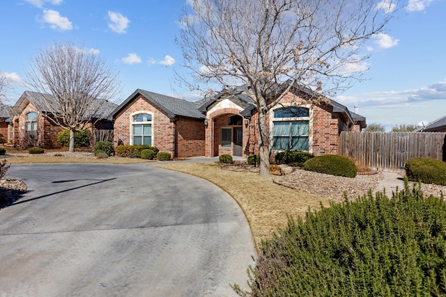 ranch-style house featuring brick siding, a shingled roof, and fence