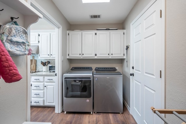 laundry area featuring cabinets, dark hardwood / wood-style flooring, and washing machine and clothes dryer