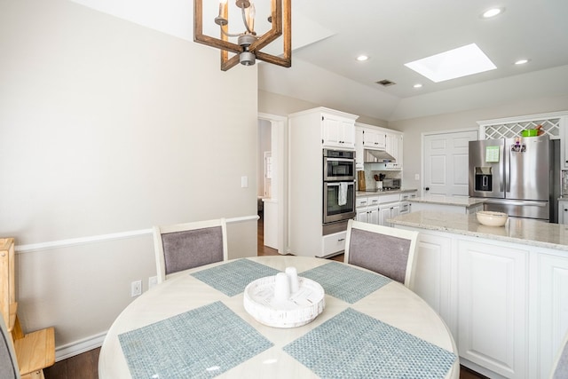 dining room with vaulted ceiling with skylight and a chandelier