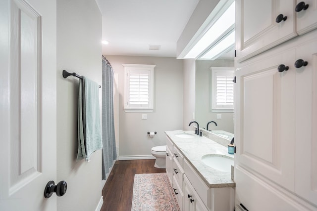 bathroom with wood-type flooring, vanity, and toilet