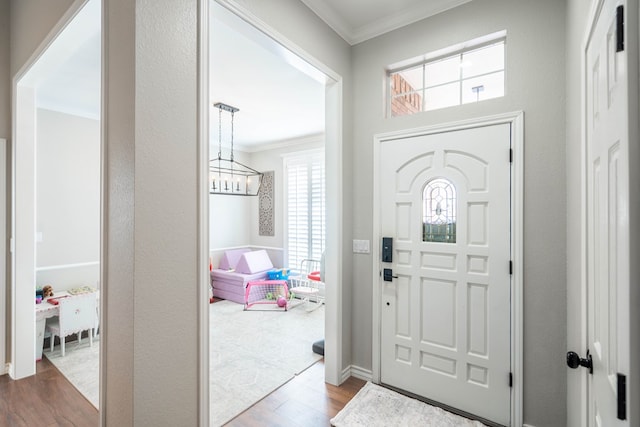 foyer featuring hardwood / wood-style floors, an inviting chandelier, and ornamental molding