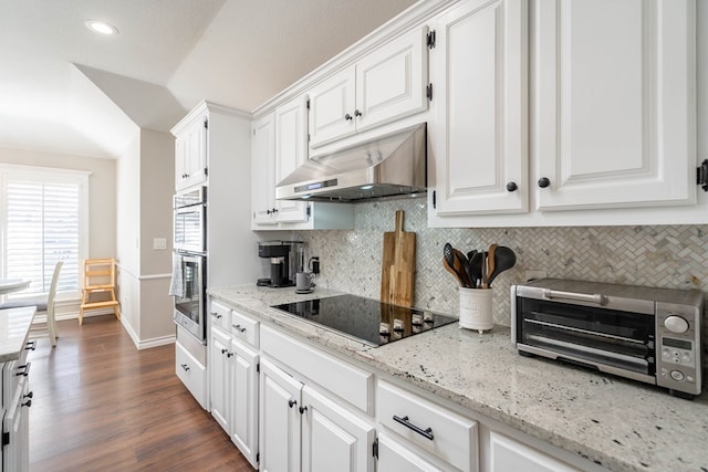 kitchen with black electric stovetop, decorative backsplash, white cabinets, and light stone counters