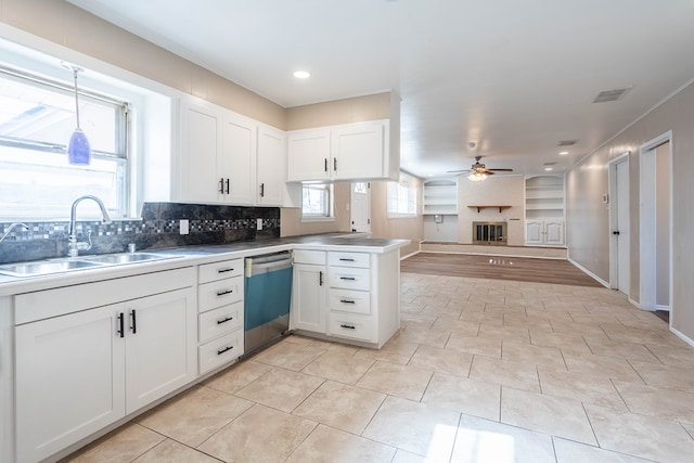 kitchen with kitchen peninsula, white cabinetry, dishwasher, and sink