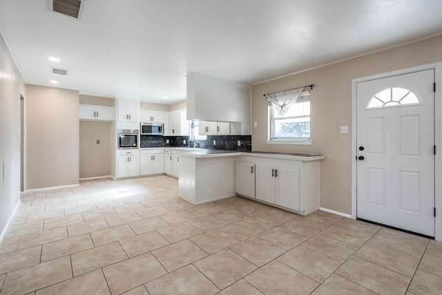 kitchen featuring white cabinets, sink, decorative backsplash, kitchen peninsula, and stainless steel appliances