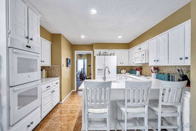 3409 Wedgwood, Midland, TX 79707 - kitchen with white appliances, light countertops, a textured ceiling, white cabinets, and backsplash