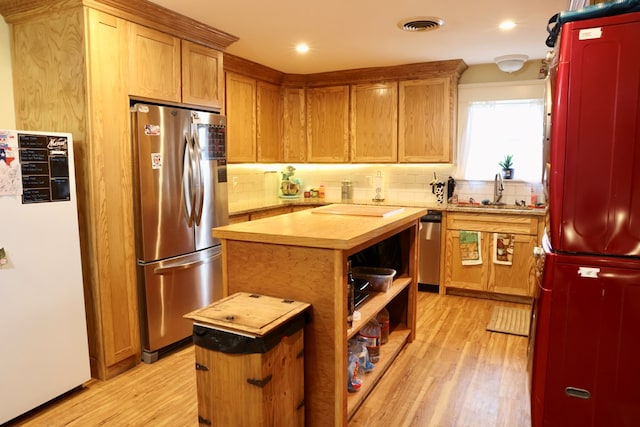 kitchen with sink, light hardwood / wood-style floors, stainless steel refrigerator, and a kitchen island