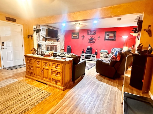 living room with beamed ceiling, ceiling fan, and light hardwood / wood-style flooring