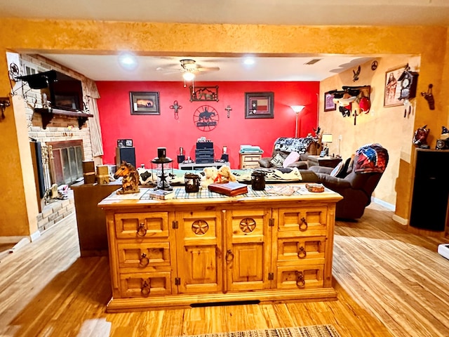 interior space with ceiling fan, a fireplace, beamed ceiling, and light wood-type flooring