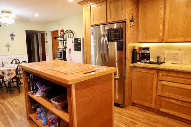 kitchen with decorative backsplash, stainless steel appliances, butcher block counters, and light hardwood / wood-style flooring