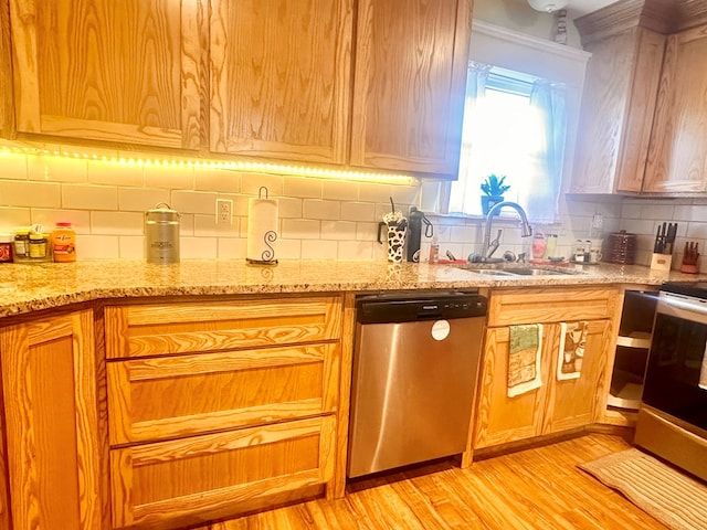 kitchen with tasteful backsplash, sink, light stone counters, stainless steel appliances, and light hardwood / wood-style flooring