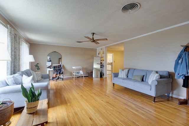 1603 Sycamore St, Big Spring, TX 79720 - living area featuring light wood-style flooring, ceiling fan, a textured ceiling, ornamental molding, and arched walkways