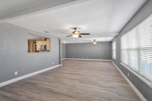 empty room with ceiling fan and light hardwood / wood-style flooring