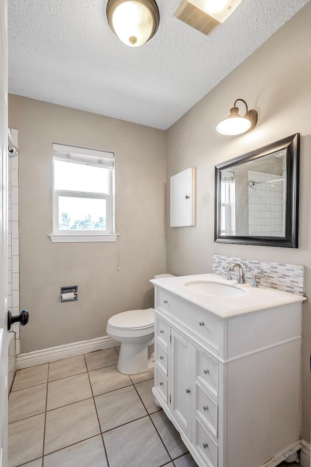 bathroom with vanity, a textured ceiling, tile patterned floors, toilet, and walk in shower