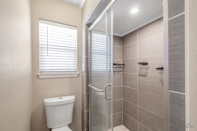 bathroom featuring a shower with shower door and toilet