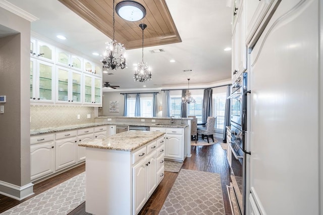 4508 Island Dr, Midland, TX 79707 - kitchen with a chandelier, appliances with stainless steel finishes, a peninsula, dark wood-style floors, and a tray ceiling